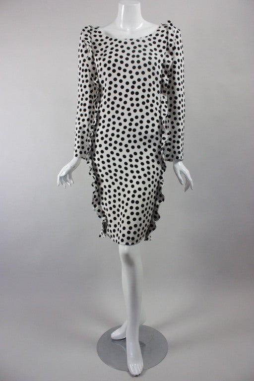 Fun dress from James Galanos circa 1980's is made out of four-ply white silk with black polka dots.  It is form fitting, has two playful ruffles sewn down the front sides, and wide boat neck.  Long sleeves have faceted button cuffs.  Center back