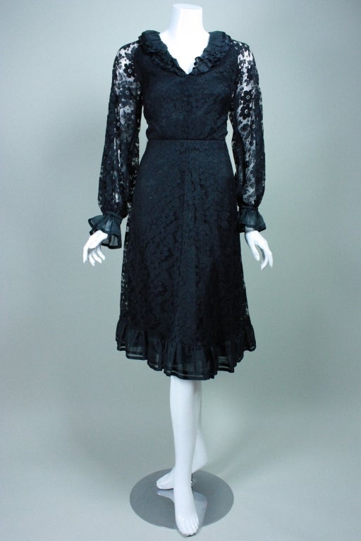Cocktail Dress circa 1970's from Hardy Amies is made out of black floral lace.  Long sleeves with ruffled snap cuff.  V-neck has double silk ruffle.  Fitted bodice.  Raglan sleeve.  A-line skirt.  Center back zipper.  Lined except for in