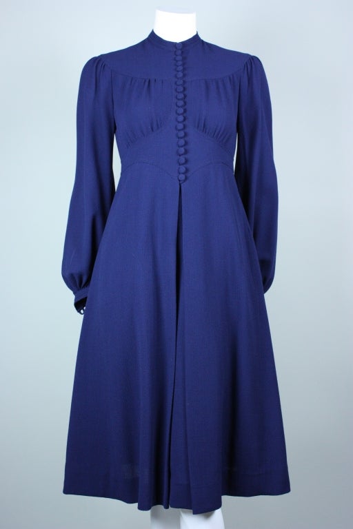1970's dress from Jean Muir retailed at Henri Bendel.  It is made out of dark blue fine wool crepe.  Fitted bodice has high, round neck and gathering along the top and bottom bust.  Front and back curving yoke.  Long sleeves with button cuffs. 