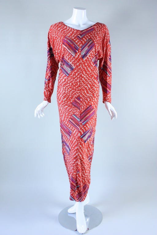 Missoni gown dates to the late 1970's through the 1980's.  It is made out of an orange-red cotton jersey with an abstracted stripe and dot diagonal print.  Rounded v-neck.  Long dolman sleeves are tapered at wrists.  Large keyhole opening in back. 