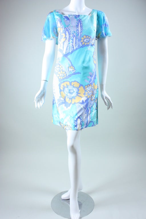 1960's dress from Sheila Follis is made out of light blue silk with a organic floral print in violet, yellow, and dark blue.  It features a squared scoop neck, short chiffon sleeves with scalloped edges, and bust darts for shaping.  Center back