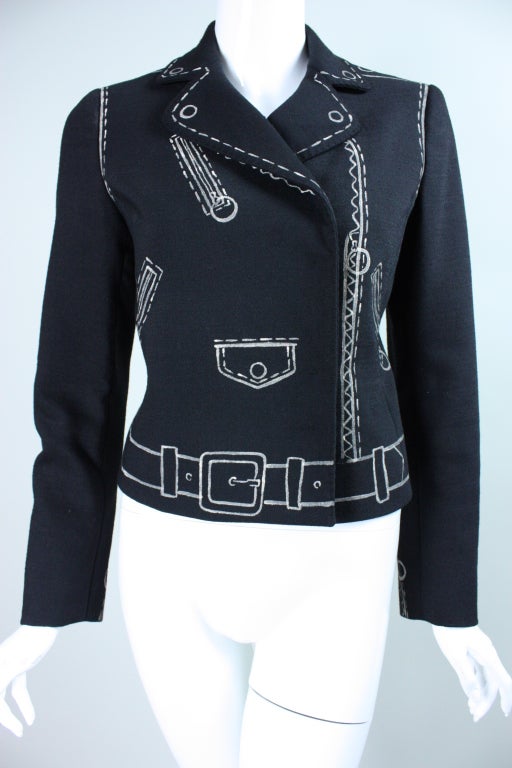Clever jacket from Moschino dates to the 1990's.  It is made out of black wool with hand-painting that emulates the details of a leather bomber jacket.  Turn-down collar with notch lapel.  Double breasted.  Hidden snap closure.  Fully