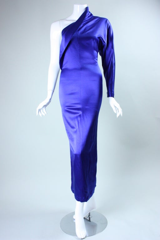 Dramatic one-sleeved gown from Krizia is made out of royal blue synthetic satin.  It is extremely tight fitting throughout the body with a dolman-style sleeve.  Fin-like protrusion extends diagonally through the bodice.  Unlined.  Side