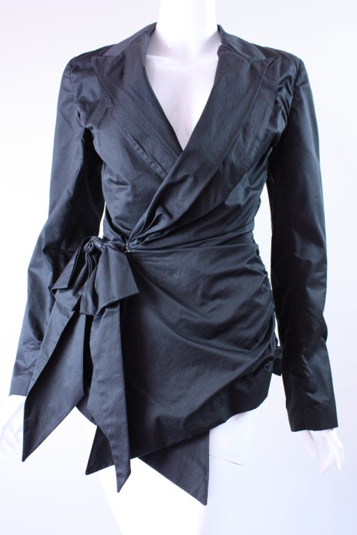 Totally unique blazer from Jean Paul Gaultier is made out of black cotton sateen.  It has a v-neck with notched lapel and an over-sized bow at right side hip.  Back is fully gathered.  Side waist hook and eye closure is concealed by bow. 