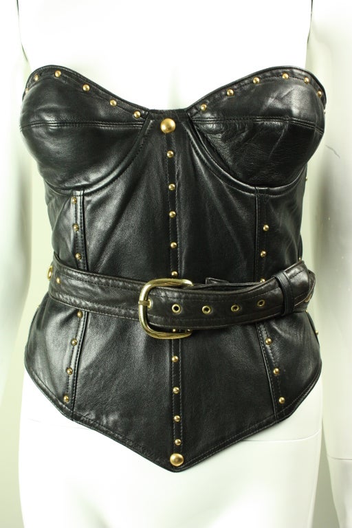 Isaac Mizrahi bustier circa 1980's through 1990's is made out of soft lambskin.  It is adorned with gold metal rounded studs.  Wrap around belt closes in the front.  Boned throughout for structure and support.  Soft cups.  The removable padded cups