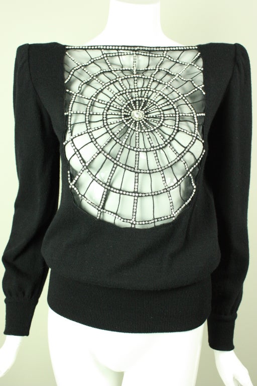 Unique sweater from Valentino is made out of black cashmere with a large center front cutout.  Cutout has been replaced with transparent black mesh over which clear faceted rhinestones have been sewn onto black spiderweb design.  Long sleeves have