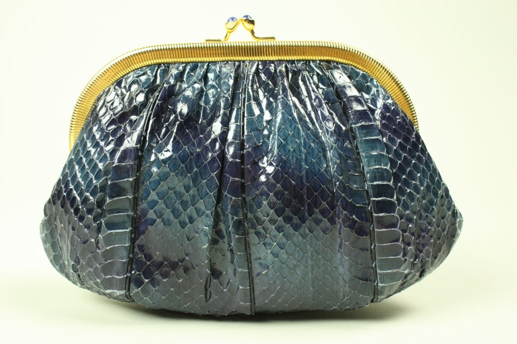 Navy blue snakeskin evening bag from Judith Leiber can be worn either as a clutch or around the shoulder.  Gold-toned frame and chain.  Kiss clasp is set with semi-precious stones.

Measurements-

Width: 4 1/2-8 1/2