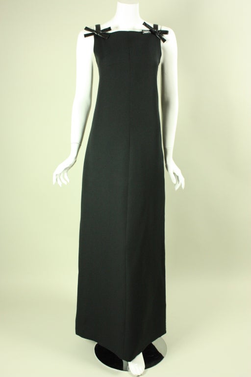 Column gown from Courreges circa 1960's is made of black polyester with vinyl straps and bows.  Squared neckline.  Full-length.  Side invisible zipper.  Lined.

Labeled size B.

Measurements

Bust: 34