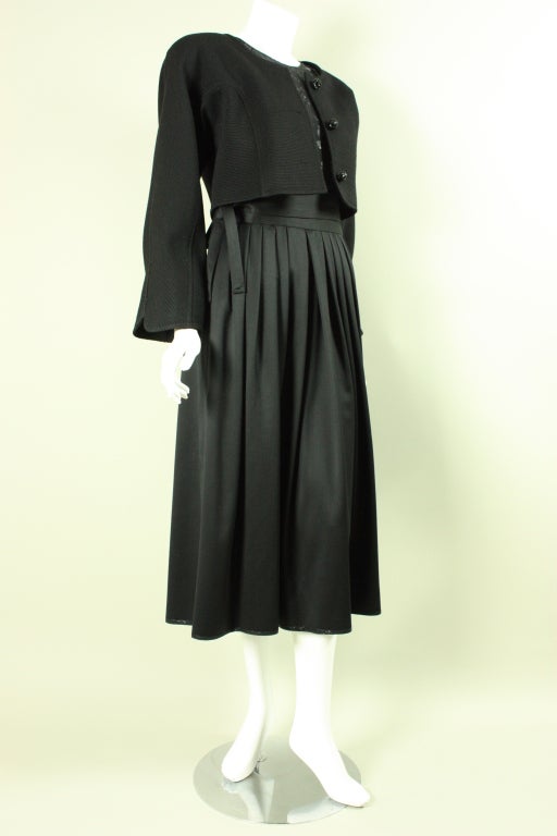 Delectable three-piece evening ensemble from Geoffrey Beene dates to the 1980's.  It consists of a jacket, blouse, and skirt.  The single-breasted jacket is made out of textured wool, has a round neck, shoulder pads, and three beaded buttons.  Sheer