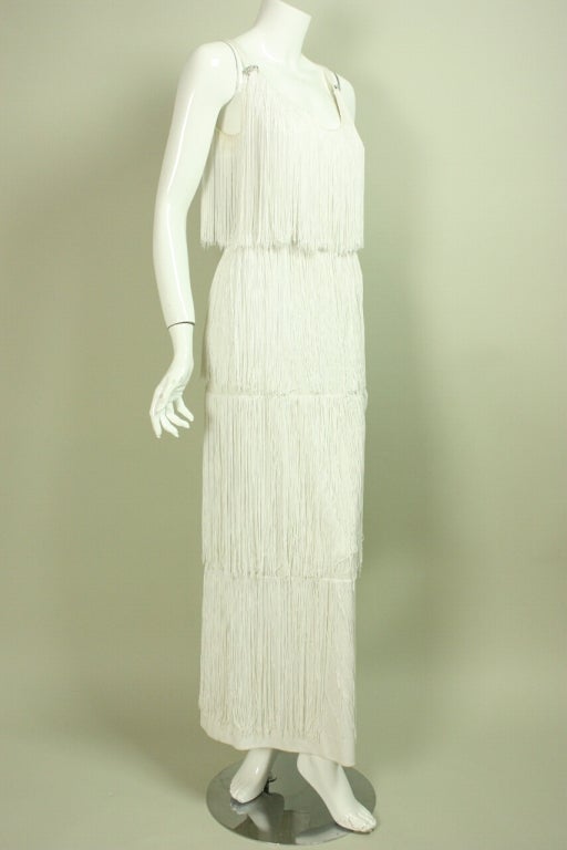 Show-stopping gown from Lilli Diamond dates to the late 1960's through 1970's.  It is made of rows of long white fringe with diamante details on the sides of the scooped neck.  Sleeveless.  Floor-length with side slit.  Center back zipper.  Lined