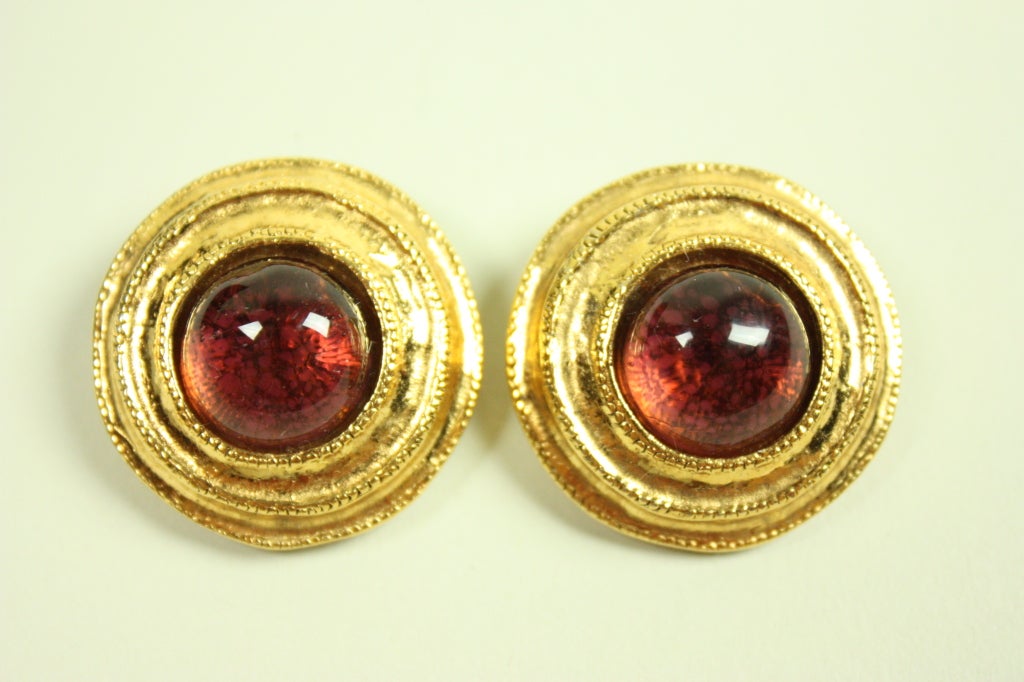 Gold-toned Chanel earrings have reddish-amber Gripoix center.  Clip-on style.

Diameter: 1 1/4