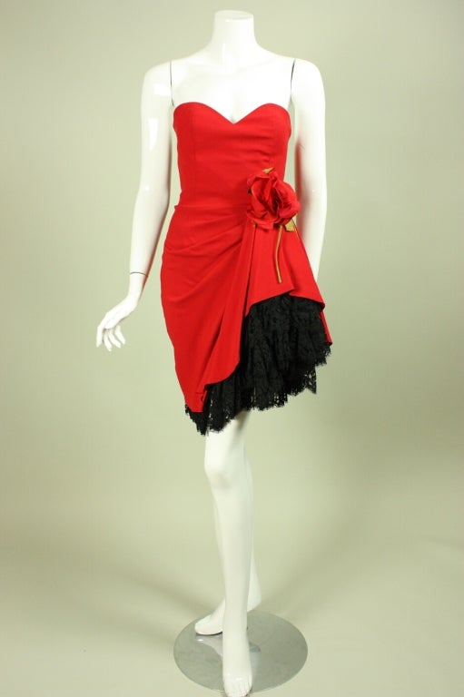 Sassy dress from Moschino Couture is made of red fabric with layers of black lace at the hem.  Large rosette detail at side waist.  Strapless.  Boned bodice.  Lined.

Labeled an IT 38, FR 34, GB 6, and US 4.

Measurements-

Bust: 30