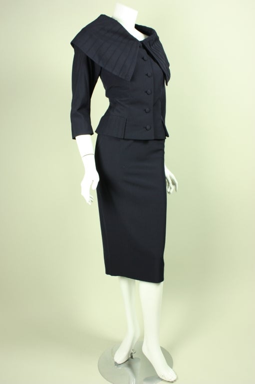Stylish late 1940's through 1950's suit from iconic American designer Don Loper is made of navy wool gabardine.  Single-breasted jacket features an unusually large portrait collar featuring pintucking throughout.  Straight skirt has back vent and