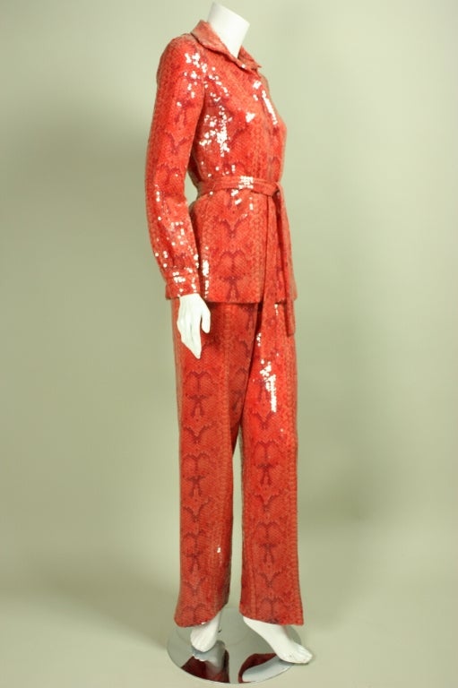 Glamorous ensemble from Bill Blass is made of red silk with a snakeskin print that is entirely covered with clear sequins.  Blouse has hidden snap closure down the center front, turn-down collar, and long sleeves with snap cuffs.  Straight pants