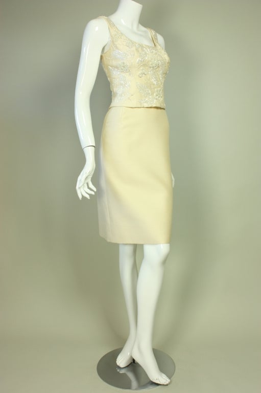 1960's cocktail dress is made of ivory silk with beading in a floral pattern on the front bodice.  Scoop front and back neck.  Sleeveless.  Fitted throughout.  Center back zipper.  Lined.

No size label.