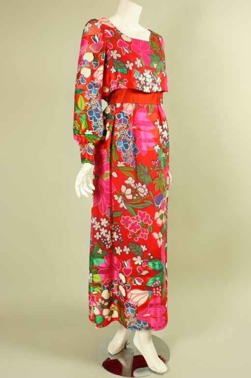 1970's Richilene gown retailed at famed L.A. boutique Elizabeth Arden.  It is made of brightly-printed red silk chiffon in a floral pattern.  Over bodice has scoop neck and long billowing sleeves that snap at the wrists.  A-line skirt is