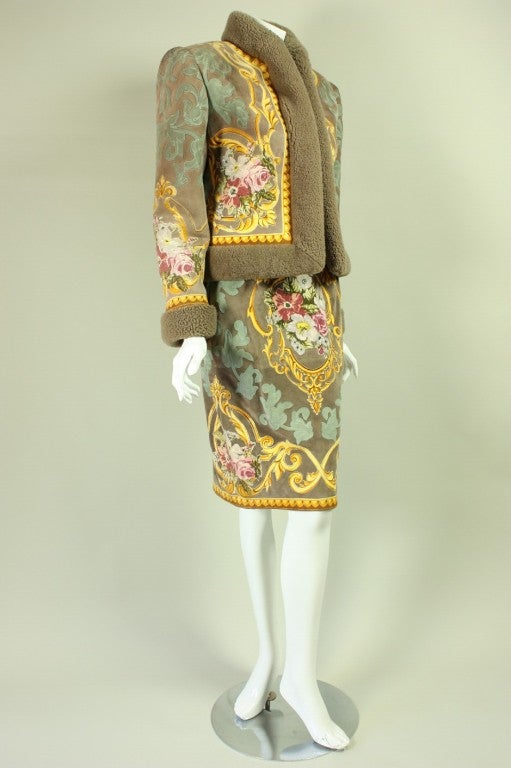 Fabulous shearling skirt suit from Valentino is made of tan suede with colorful appliques throughout depicting flowers and scrolling patterns.  Jacket has shearling trim along cuffs, collar, and center front as well as center front hook and eye
