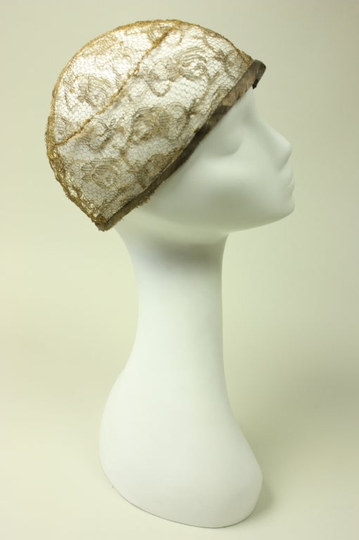 Delicate skull cap is made of metallic lace in a floral pattern.  It dates to the 1920's when tight-fitting caps were all the rage.  Band of lamé fabric trims the edge.  Unlined.

Interior circumference: 23
