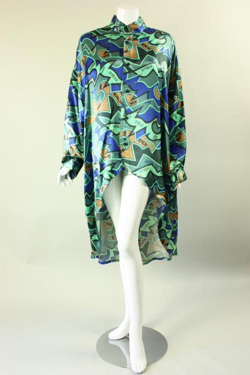 Unusual blouse from Kansai Yamamoto dates to the 1980's and is made of a boldly printed fabric in shades of blues and greens.  Oversized with tapered batwing sleeves that have buttoned cuffs.  Center front button closure.  Unlined.

Labeled size
