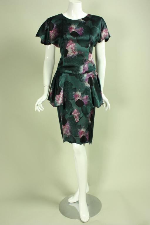 Flirty cocktail dress from Holly's Harp is made of dark green silk with an allover splotchy print.  Fitted bodice has round neckline and dolman sleeves.   Straight skirt with peplum.  Center back covered button and zip closures.  Bodice is lined. 