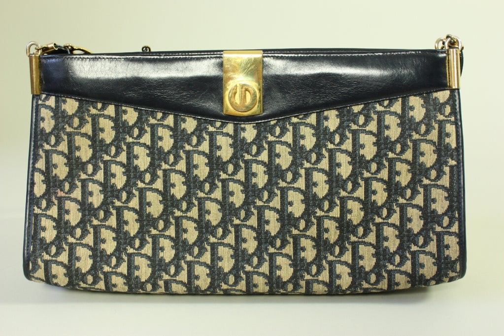 Christian Dior handbag dates to the 1970's and is made of beige canvas with a navy monogram print.  Gold-toned hardware with leather strap.  Leather lined with three interior zippered compartments.  Matching change purse has snap closure and is
