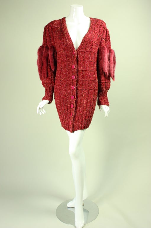 Dark pink metallic cardigan or sweater dress dates to the 1980's.  It features narrow pelts of dyed mink that are attached to the upper sleeve.  Deep v-neck.  Ribbed cuffs and hem.  Button closure.  Unlined.

No size label.

Measurements-
Bust: