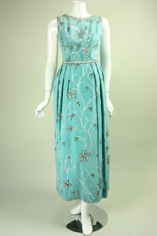 Philip Hulitar gown is made of robin's egg blue cotton velvet and dates to the late 1950's through the 1960's.  It is adorned allover with white and silver sequins in a scrolling floral pattern.  The fitted bodice is sleeveless and has a round neck.