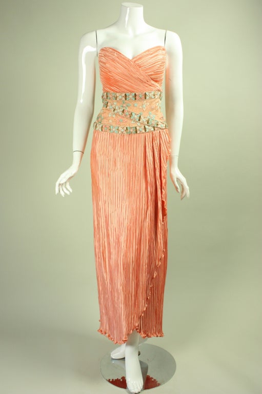 Strapless gown from Mary McFadden's couture line is made of peach pleated silk.  It has a wide waistband that is adorned with various types of embroidery as well as gold seed and bugle beads.  Center back zipper.  Fully lined.

No size