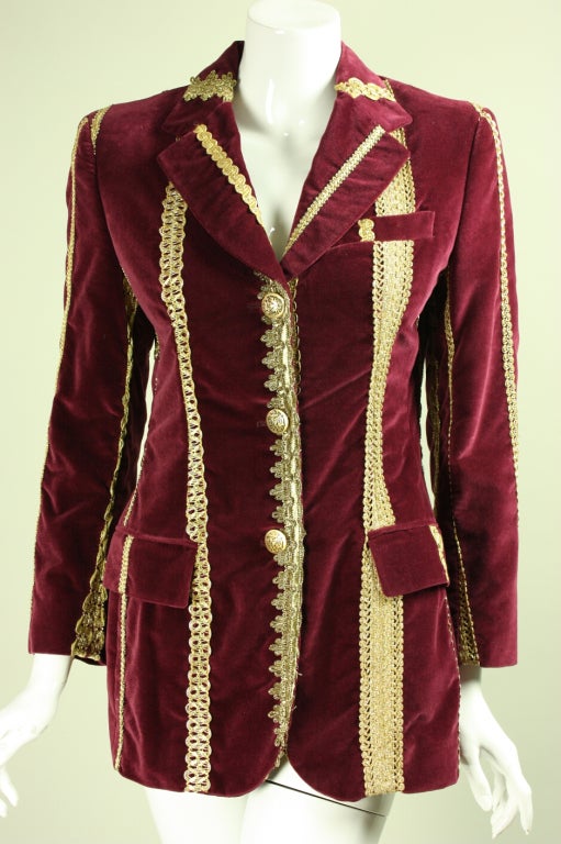 Wine-colored cotton velvet blazer from Dolce & Gabbana likely dates to the 1990's.  It features a variety of gold bullion trims that are sewn on to form a pattern of vertical stripes.  Single-breasted.  Notched lapel. Flap pockets at hip.  Fully