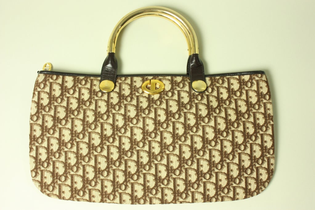 Vintage Christian Dior monogrammed handbag dates to the 1970's.  It has gold-toned hardware, zip top with a CD pull, and brown leather lining.  

Measurements-

Length: 8