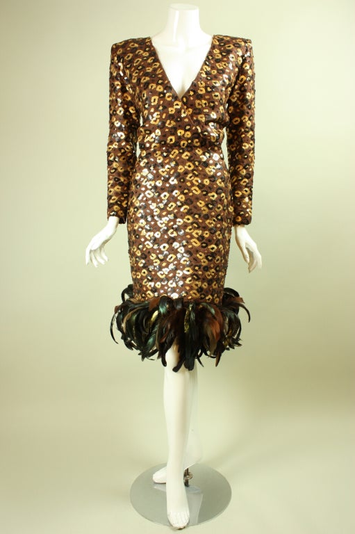 Fun cocktail dress from Givenchy dates to the 1980's through early 1990's and is made of brown chiffon that is covered with black and gold sequins.  Hem is fully trimmed with iridescent feathers.  V-neck.  Long sleeves.  Fitted throughout.  Side