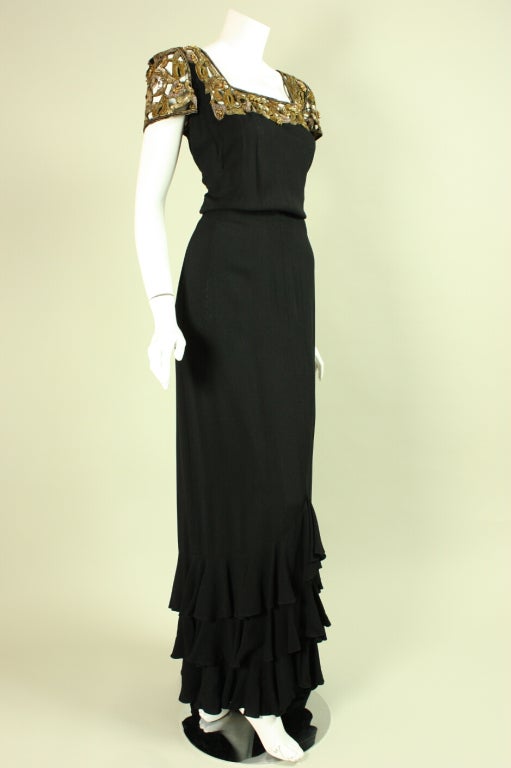 Elegant gown that dates to the 1930's is made of black crepe with a gold sequined and beaded openwork neckline and sleeves.  Fitted throughout.  Ruffle detail at hem and slight train.  Unlined.  Side zip closure.

Please contact us before