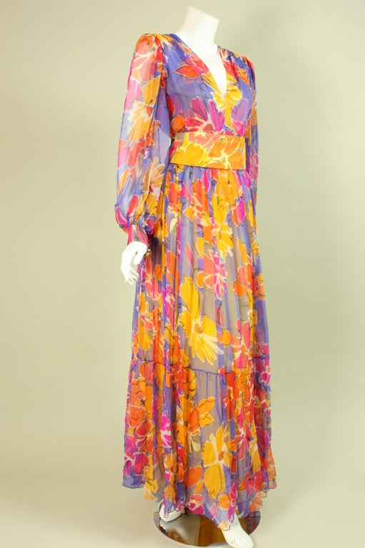 Colorful gown from Givenchy dates to the late 1970's through 1980's and is made of multicolored silk chiffon in shades of yellow, purple, orange, and red.  Fitted bodice has deep v-neck and long billowing sleeves with buttoned cuffs.  Full length