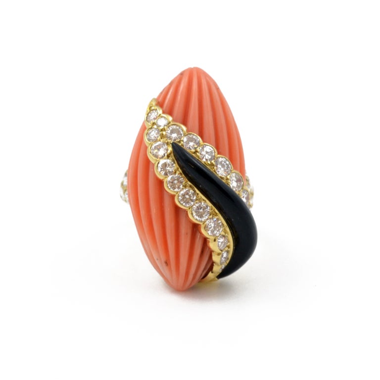 A carved coral, diamond and onyx set ring, mounted in 18ct yellow gold. With the maker's mark of Andre Vassort.