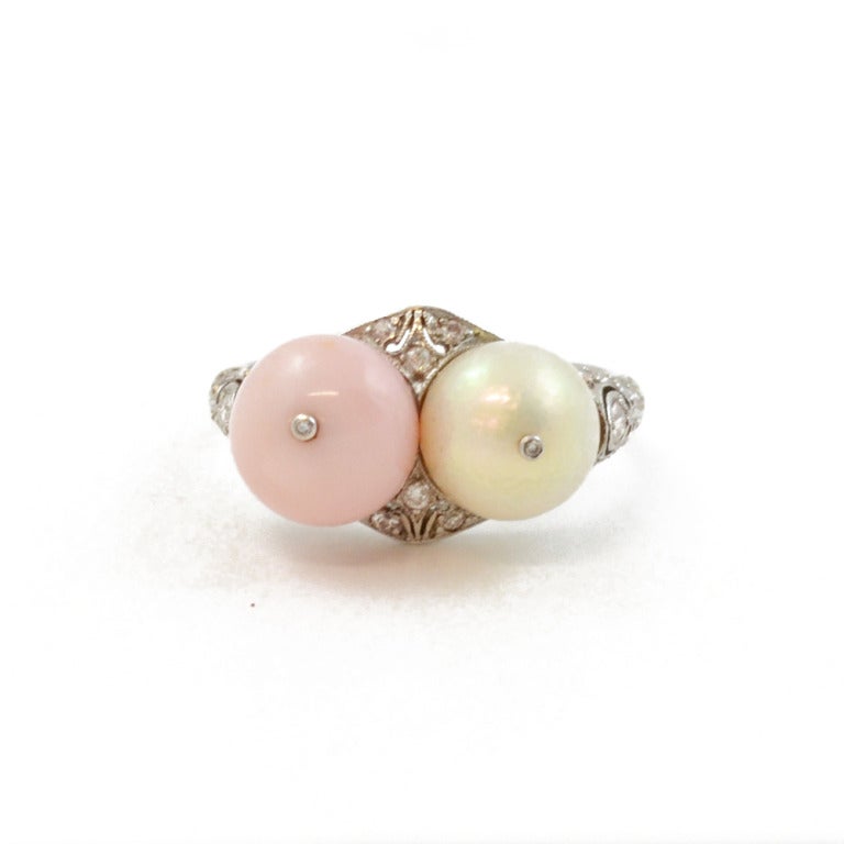 An Edwardian ring set with one conch pearl and one natural Oriental pearl, each with a small diamond to centre, with an intricate diamond set platinum mount.