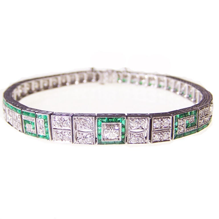 An Art Deco emerald and diamond set bracelet, decorated in the stones with a Greek key pattern. Mounted in platinum.
