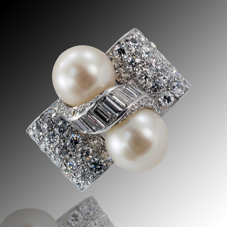 Restrained decadence in a design composed by a pair of 11 mm cultured pearls between a swirl motif of channel-set baguette diamonds, on an undulating ground of pave diamonds, the diamonds totaling approximately 5.00 carats, approximately one inch