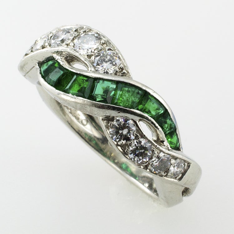 PLATINUM BAND ENTWINED WITH 12 EMERALDS AND 11 DIAMONDS. DIAMONDS TOTAL .70CT