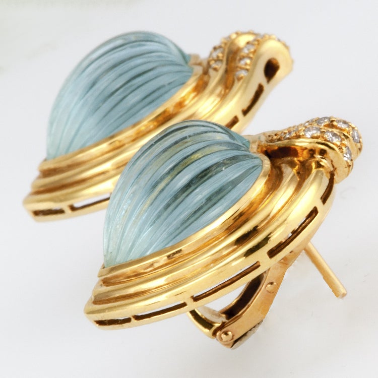 These lovely Carrera y Carrera earrings feature a pair of bezel-set, heart-shaped, beautifully carved cabochon Aquamarines totaling approximately 22 1/2 carats, within a conforming stepped gold frame accented with diamonds totaling approximately 1/4