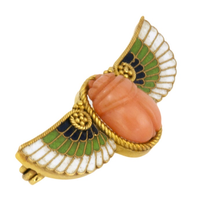 Antique Egyptian Revival  Scarab Brooch, Circa 1880
The design centers upon a lovely carved coral scarab, bezel-set to outstretched  splendid wings decorated with white, green and blue enamel on 18kt gold