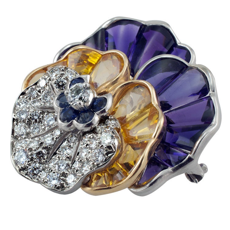 This realistic sculptural designed pansy pin with jewel tones of  amethyst and yellow sapphires are custom cut to fit, along with diamonds  and blue sapphires. The diamonds total 1.28cts.  Made in platinum and 18kt gold.