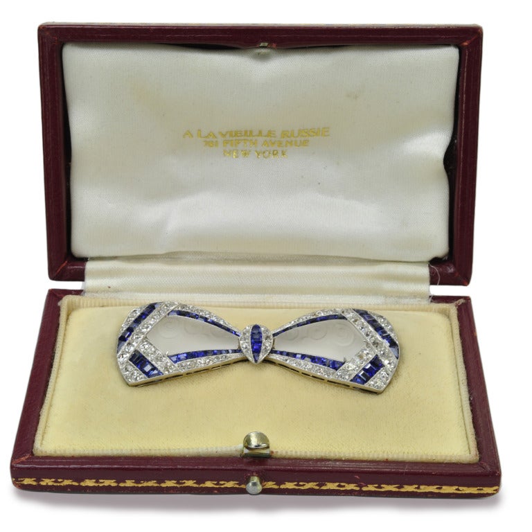 Provenance: Jacqueline Kennedy:
Art Deco rock-crystal, sapphire and diamond bow brooch, owned by Jacqueline Kennedy, features a pair of carved and frosted rock-crystal panels, framed by calibre-cut sapphires and old European-cut diamonds totaling