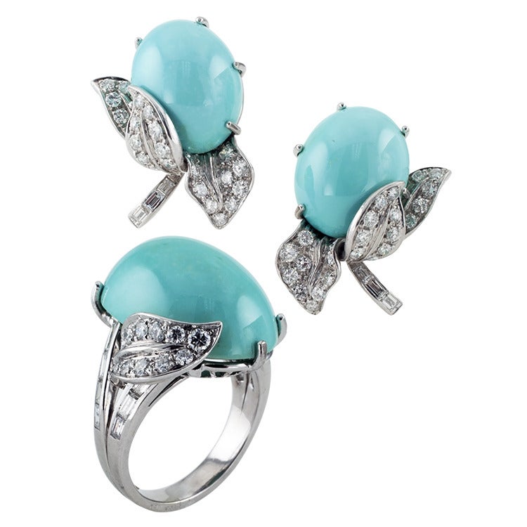 This beautiful floral inspired designed ring in 18kt white gold features an oval turquoise cabochon flanked by a pair of petals to the split shank all set with diamonds totaling approximately 1.50 carats.  The matching earrings sold separately, item