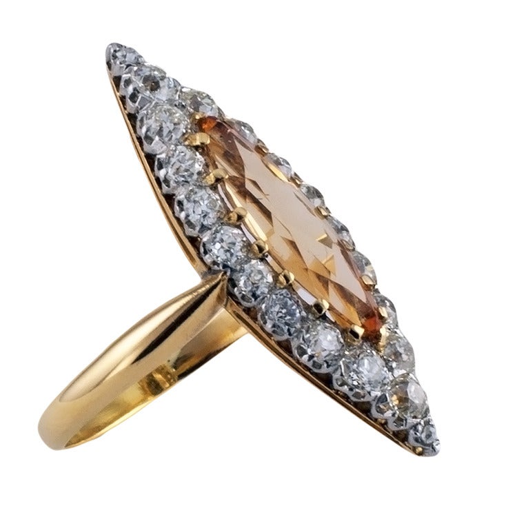 A Beautiful Antique Imperial Topaz & Diamond Ring, Circa 1900
The navette-shaped design showcasing a marquise imperial topaz weighing approximately 2.00 carats, within a conforming border formed by twenty diamonds set in platinum and totaling