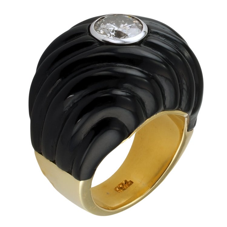 Carved Black Jade and Diamond Ring

Sensuous fluted lines carved into black jade add a sense of mystery to the bezel-set round brilliant cut diamond  weighing 1.13 carats, approximately I1 clarity and G color.  What magic keeps it in place?  Touch
