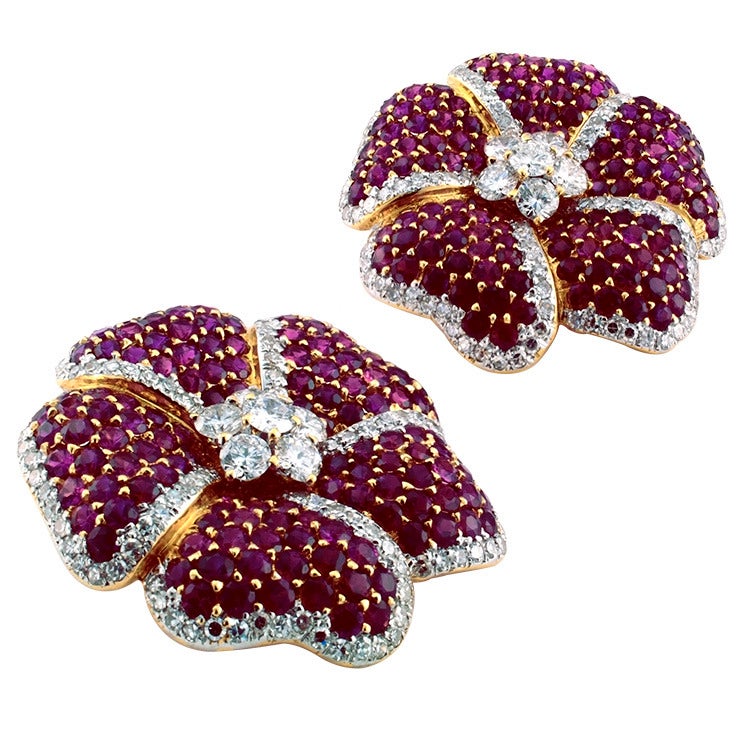 Plucked from the garden of earthly delights these beautiful flower shaped designed earrings feature ruby petals bordered with diamonds, as well as diamond clusters in the centers, the rubies totaling approximately 8.50 carats and the diamonds