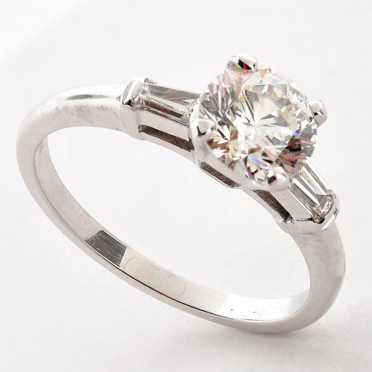 A very beautiful diamond ring in what is for sure one of the most classic and traditional types of settings, the round diamond with baguette shoulders.  The  
modern round brilliant diamond weighs 1.01ct  (H, VS2  EGL cert).  The two
tapered