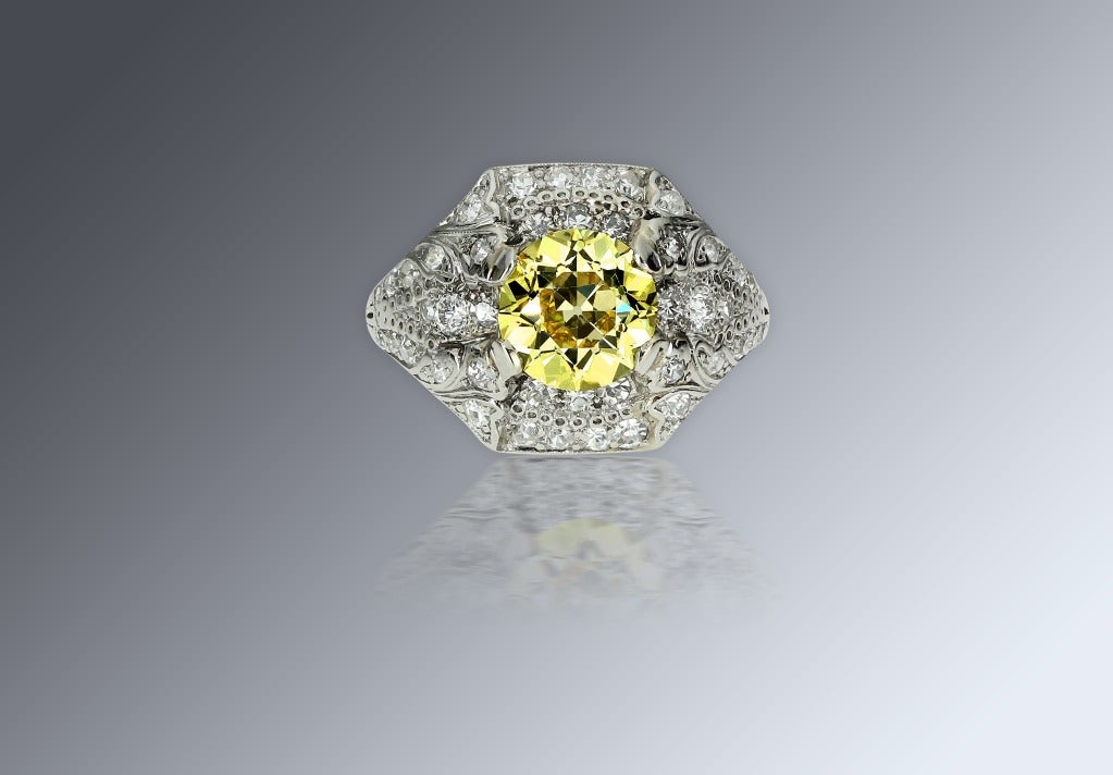 The rare and beautiful slightly domed design centers upon a 1.77 carats old European-cut diamond accompanied by a report from GIA stating that the diamond is fancy yellow color and VS1 clarity, forty-four smaller white diamonds totaling