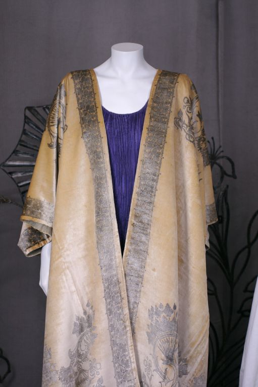 Fortuny translated the caftan as a loose fitting outer garment, usually made out of silk velvet crepe or gauze the fitted back and open front allowed for elaborate stenciled decoration and venetian bead trim. 

The hand stenciling is done with