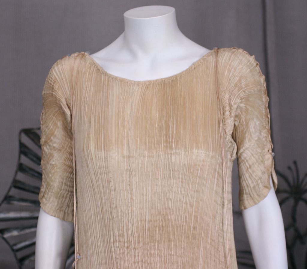 This dress is made of finely pleated  light cafe au lait colored silk with silk cording along side seams, and multicolored glass beads threaded through the cording. <br />
<br />
Named after a Greek classical sculpture, the Delphos Gown was a